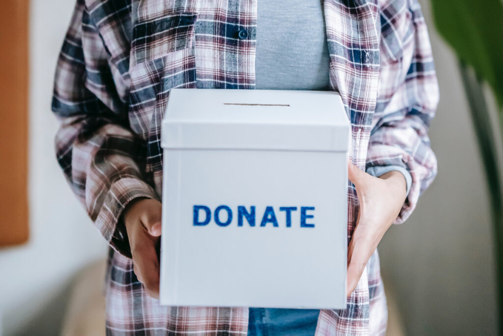 Person holding a white box with donate written across it.